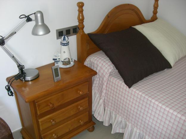 Dormitorio en pino macizo color miel con dos camas y mesita de noche