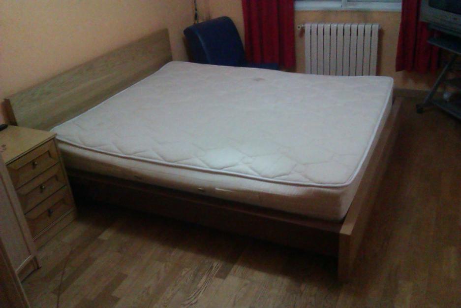 Cama muy grande, colchón y somier con cabecero y pies de madera.