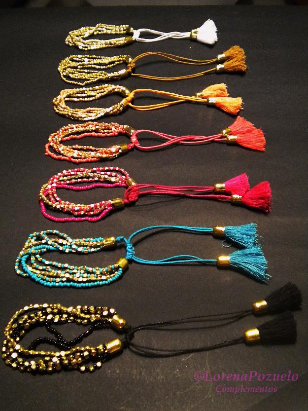 Conjunto de pulseras en varios colores realizadas con engarces dorados y borlones a juego.